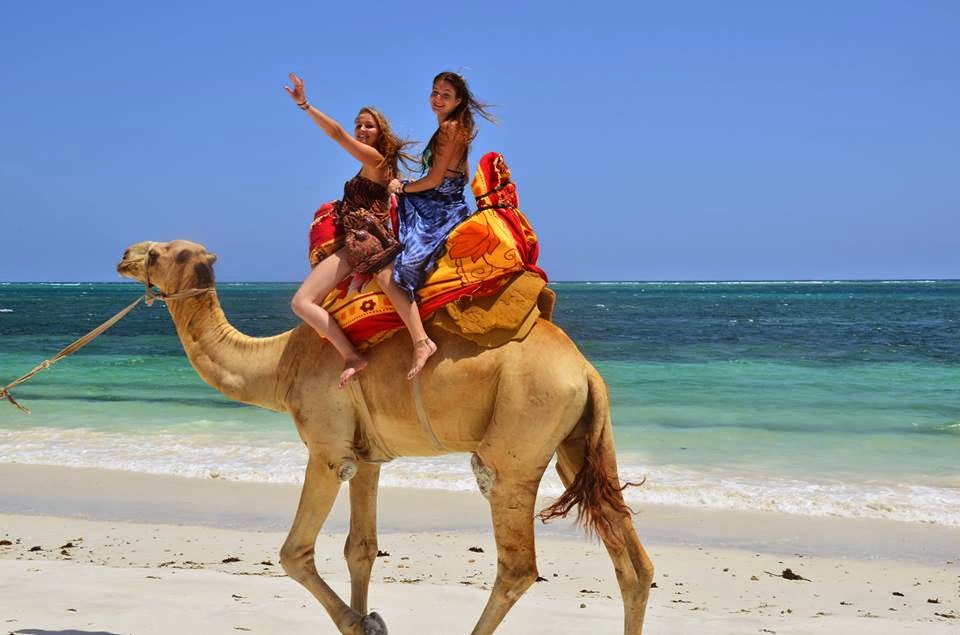 Two volunteers riding a camel along the Kenyan coast